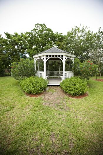 a white gazebo with a bench in the middle of a grassy area
